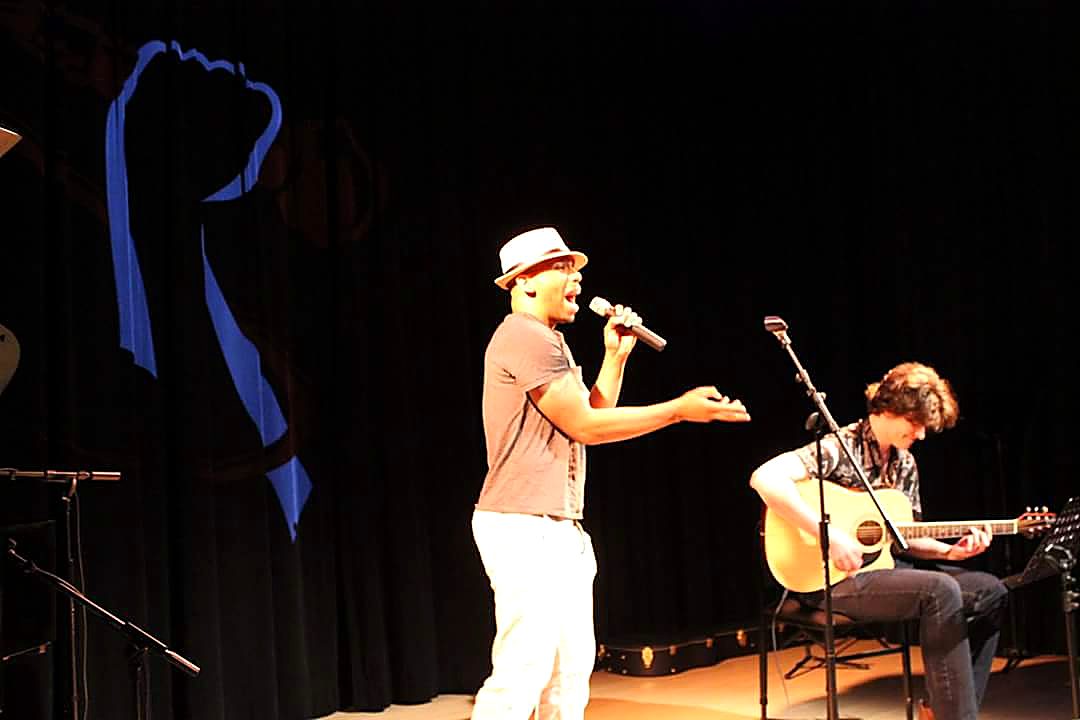 NoMatch performing live on stage with an acoustic guitarist