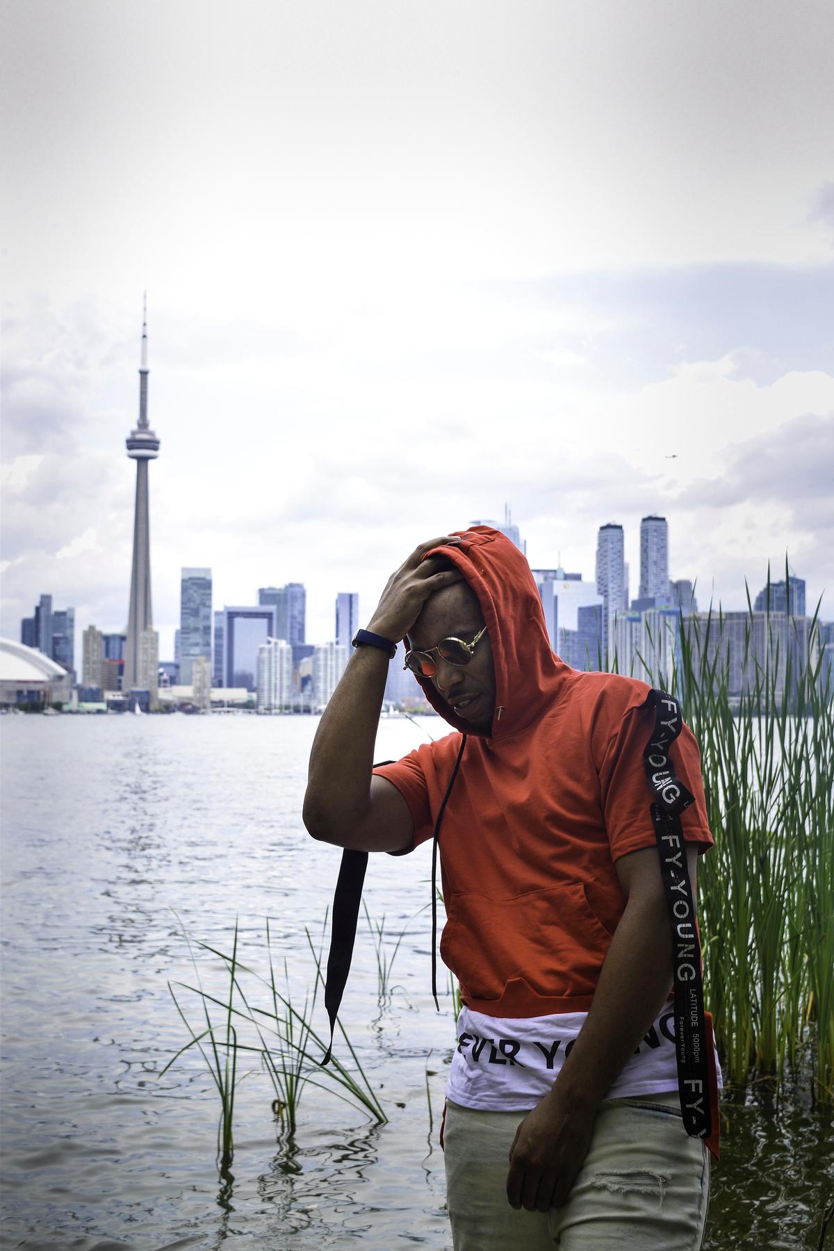 NoMatch standing by the water with the Toronto skyline and CN Tower behind him