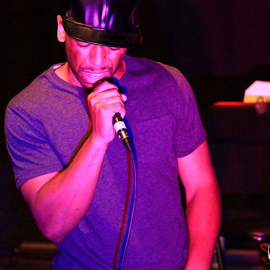 NoMatch singing into a microphone under purple stage lighting